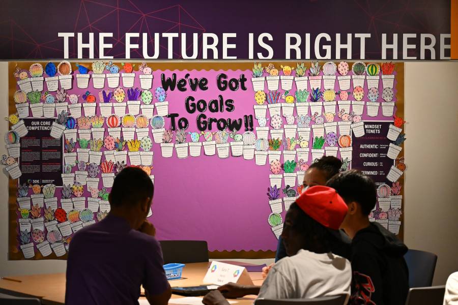 A classroom board at the 3DE Washington Technology Magnet school with students working.